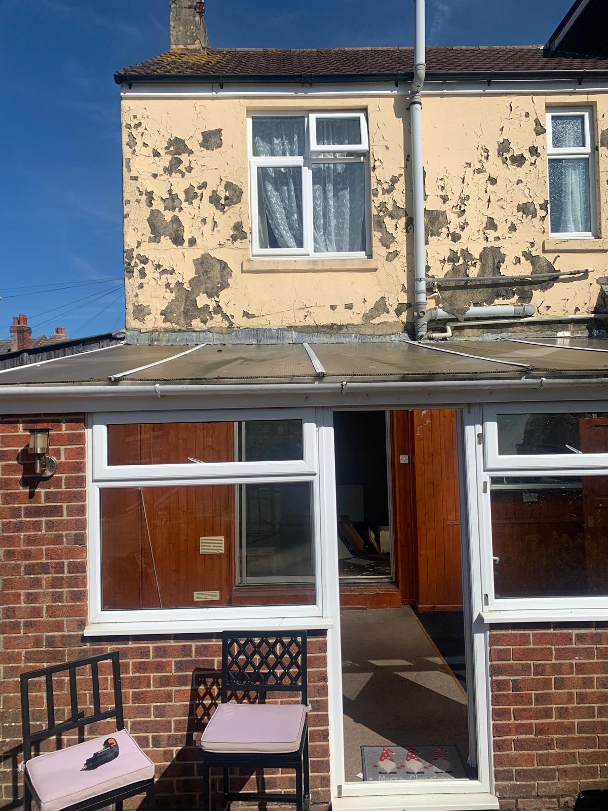 Rear of the property before work — peeling render, dated extension